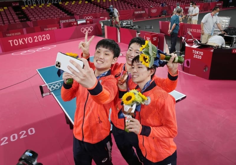 東京五輪の男子団体で獲得した銅メダルを手にし、記念撮影する（左から）張本智和、水谷隼、丹羽孝希＝２０２１年８月、東京体育館