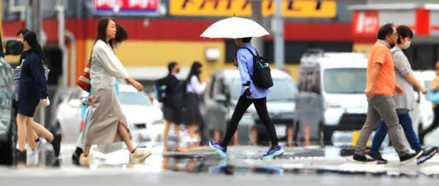 強い日差しが照り付け、路面に現れた水たまりがあるように映る現象「逃げ水」＝２０日午後、宮崎市老松２丁目