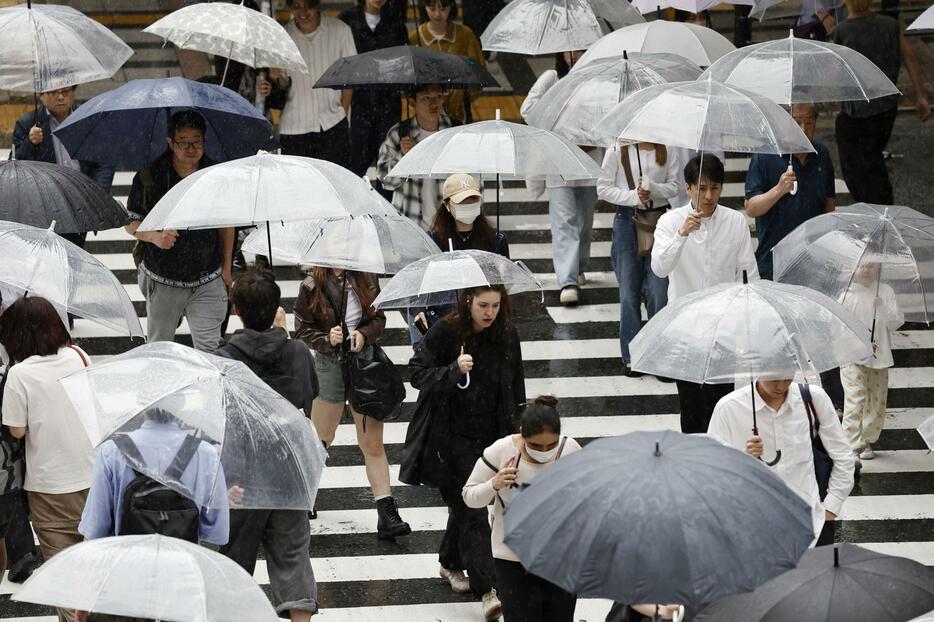 雨の中、傘を差して歩く人たち＝28日午後2時47分、JR大阪駅前