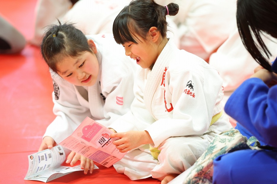 『思春期柔道ガールのエチケットガイド』を手にする小学生の女子選手たち