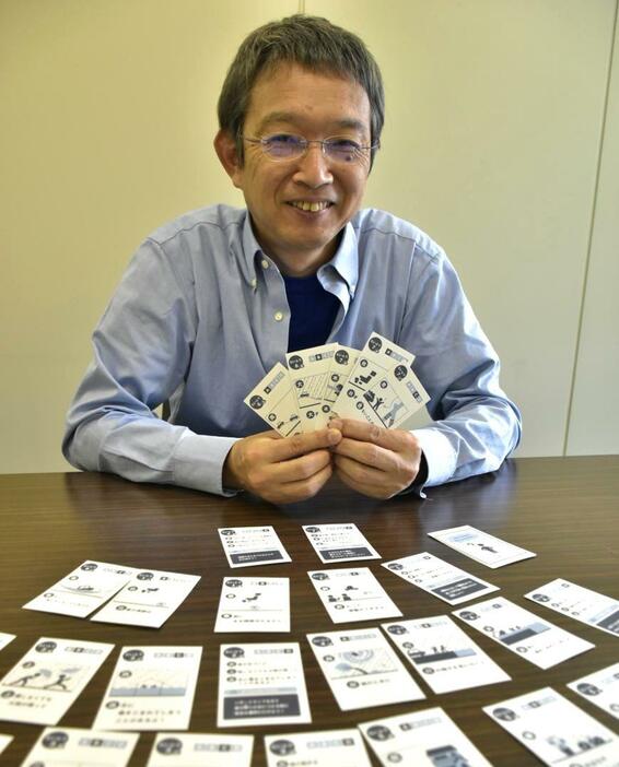 防災カードゲームの「台風編」を手に持つ国土技術政策総合研究所の長屋和宏さん=つくば市旭の同研究所