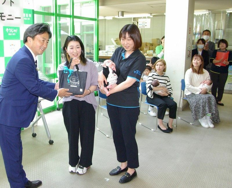 片岡市長（左）からギフトを贈られる家族