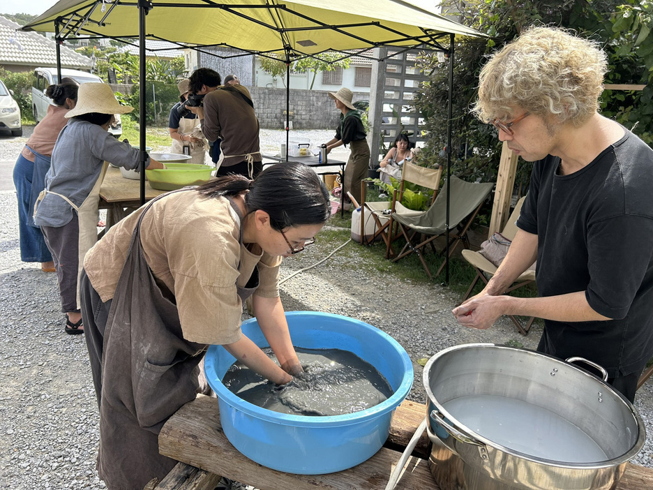 沖縄の人たちに奄美の泥染めを教える金井志人さん（右）＝4月19日、沖縄県今帰仁村