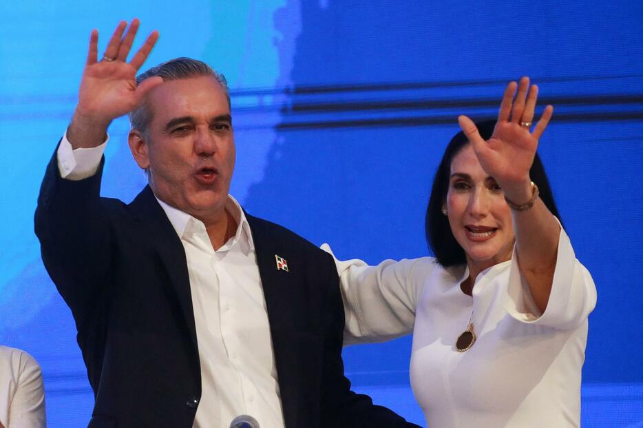 ドミニカ共和国大統領選の開票の途中経過を受け、妻（右）とともに手を振るアビナデル氏＝19日、サントドミンゴ（ロイター＝共同）