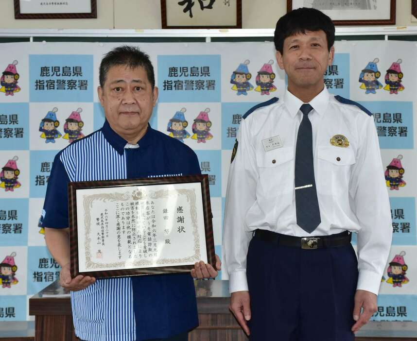 うそ電話詐欺を防ぎ、感謝状を手にする鎌田努さん（左）＝指宿市の指宿警察署