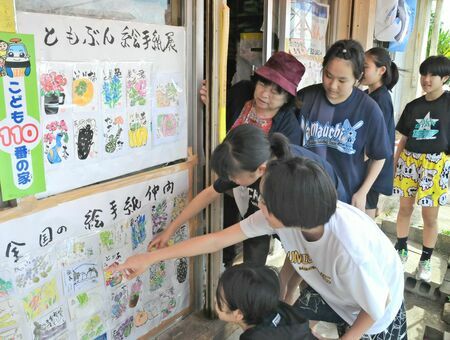 全国各地から比嘉典子さん（左奥）に届いた絵手紙を眺める子どもたち＝４月２３日、沖縄市山内の学生服の店「ともぶん」