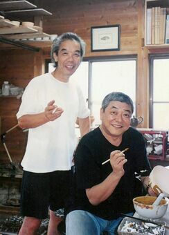 通い続けた唐津市北波多の呑楽窯で絵付けをする中尾彬さん。左は窯元の小杉昌興さん＝１９９９年８月（小杉さん提供）