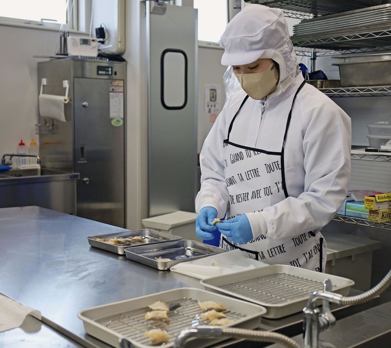 北海道白糠町にある「イミュー」の加工場で、ホッキ貝の処理をする作業員＝3月