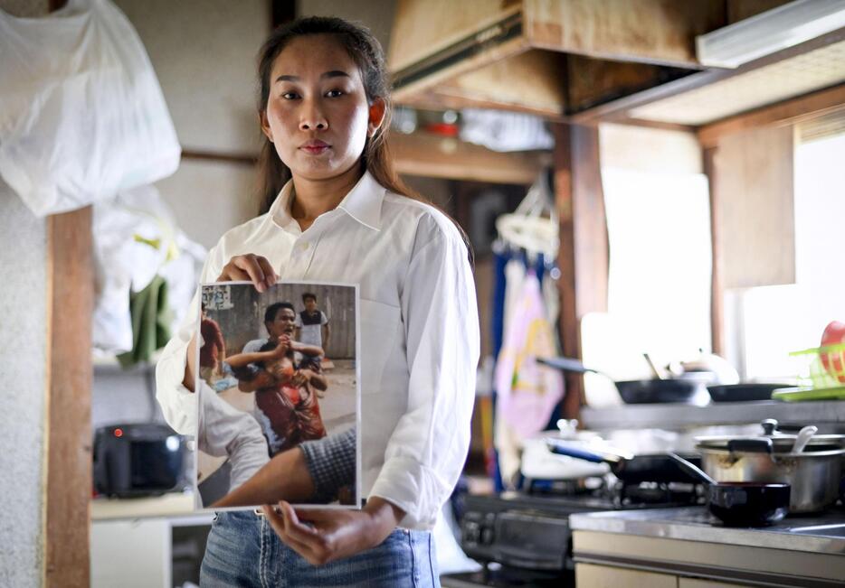 治安部隊の銃撃を受けた夫の写真を手にするカット・ソムニアンさん＝2024年4月、神奈川県内