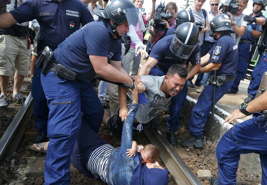 警官によって引き離される移民の男性＝2015年9月3日（写真：ロイター/アフロ）