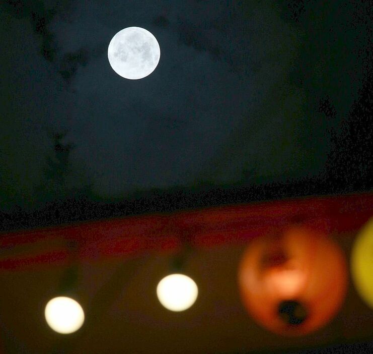[写真]大阪・新世界からもくっきりとした月を眺めることができた。飲食店の提灯なども目に入る＝27日午後11時半ごろ、大阪市浪速区で