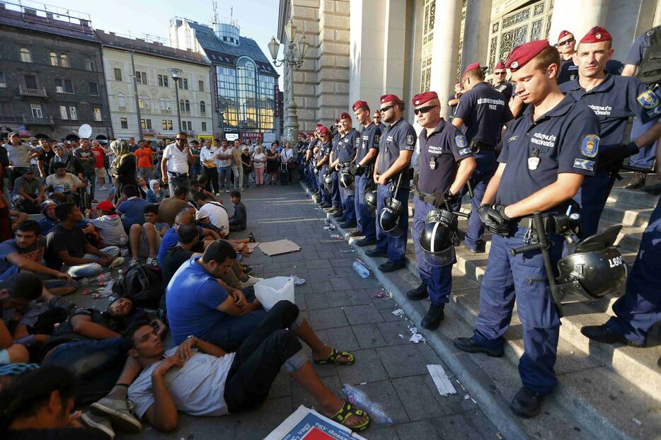 ハンガリー、ブダペスト東駅前に座り込む移民と入り口を封鎖する警官＝2015年9月1日（写真：ロイター/アフロ）