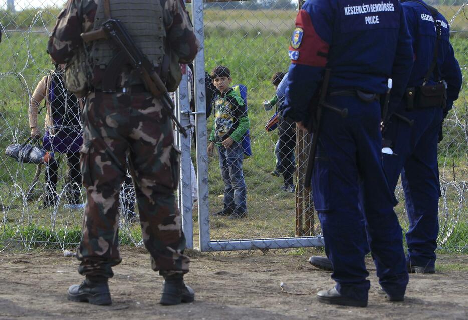 セルビア側から兵士と警官を見つめる子ども＝2015年9月15日（写真：ロイター/アフロ）