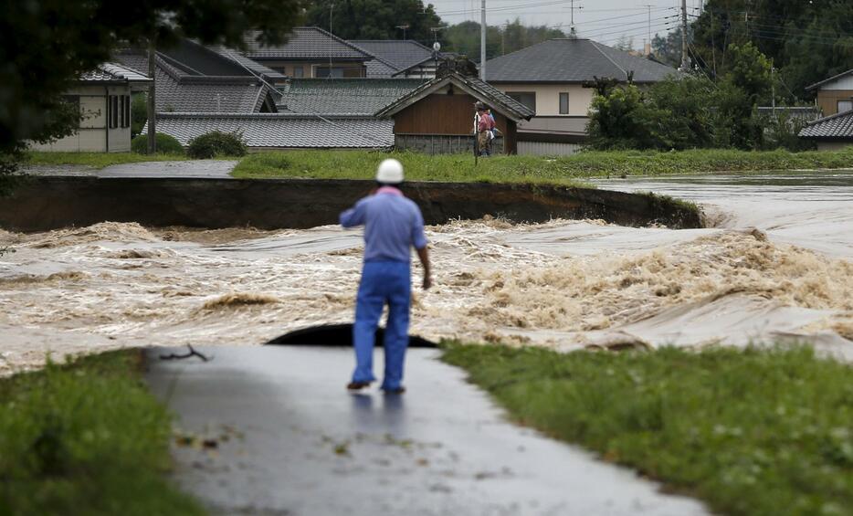 氾濫した鬼怒川を見つめる住民＝2015年9月10日（写真：ロイター/アフロ）