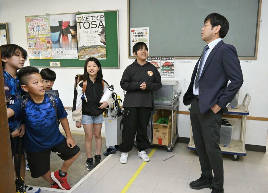 学校が再開し、高知県宿毛市の市立山奈小で校長（右端）に迎えられる児童＝19日午前