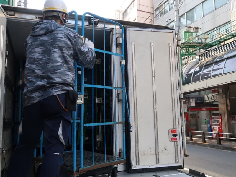 トラックの荷台で作業する運転手＝３月