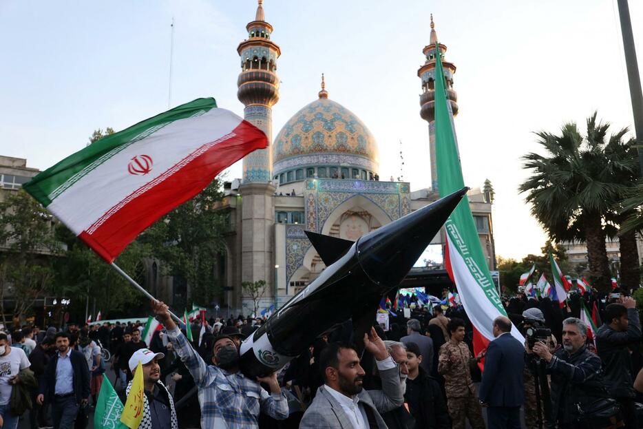 イランのミサイルの模型を掲げ、イスラエルに対する攻撃を祝福するイラン人ら＝15日、テヘラン（ロイター＝共同）