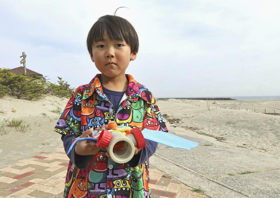 海岸のごみで作った作品を手にする上杉舞弦君＝15日、愛知県南知多町