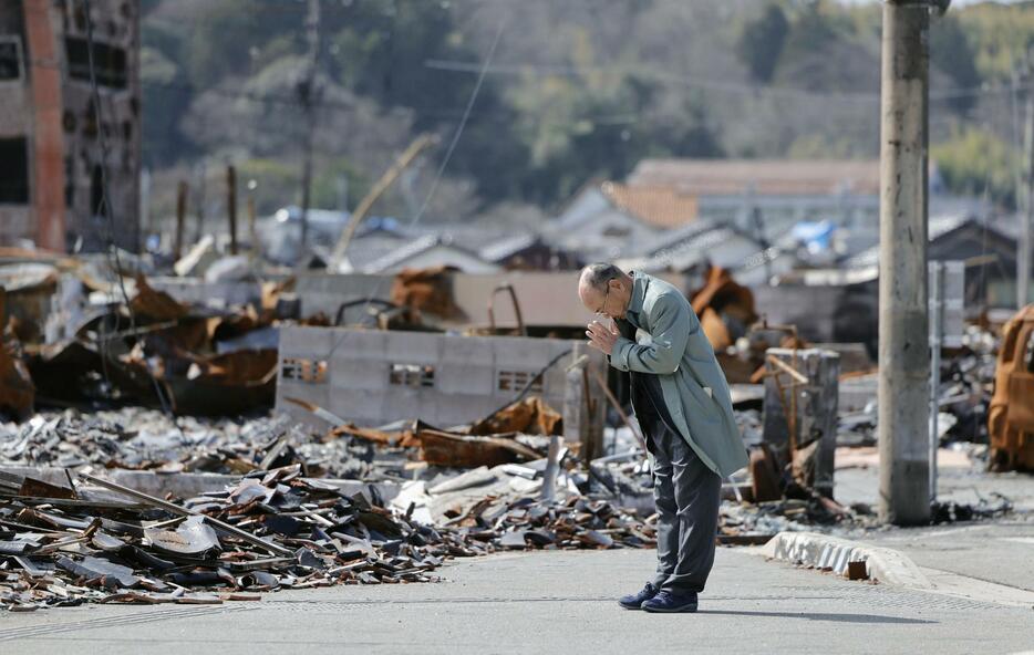 「輪島朝市」周辺の焼け跡に向かい、手を合わせる男性＝1日午後、石川県輪島市