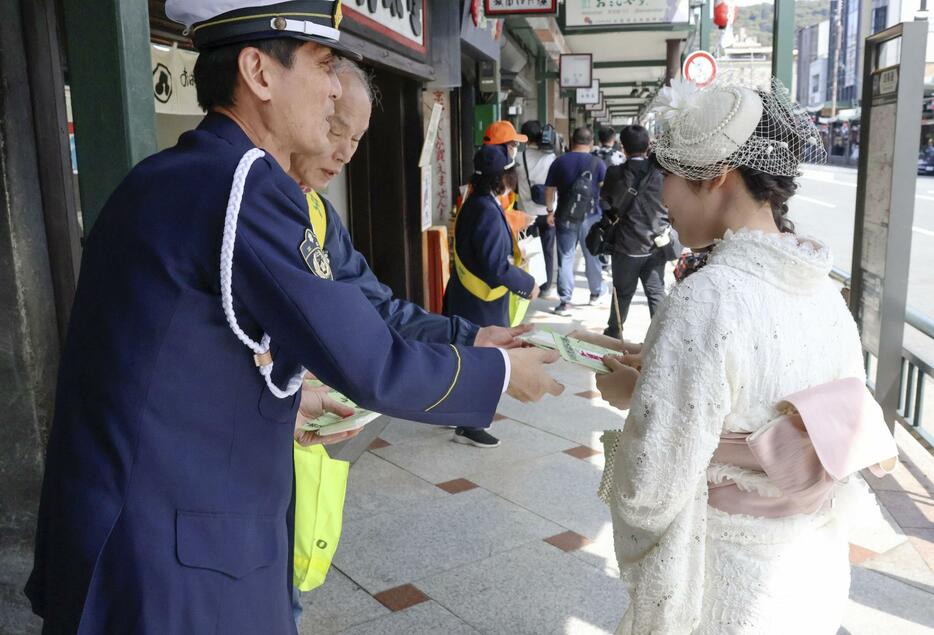 歩行者にチラシ付きのポケットティッシュなどを配り、交通安全を呼びかける京都府警の警察官ら＝12日午後、京都市