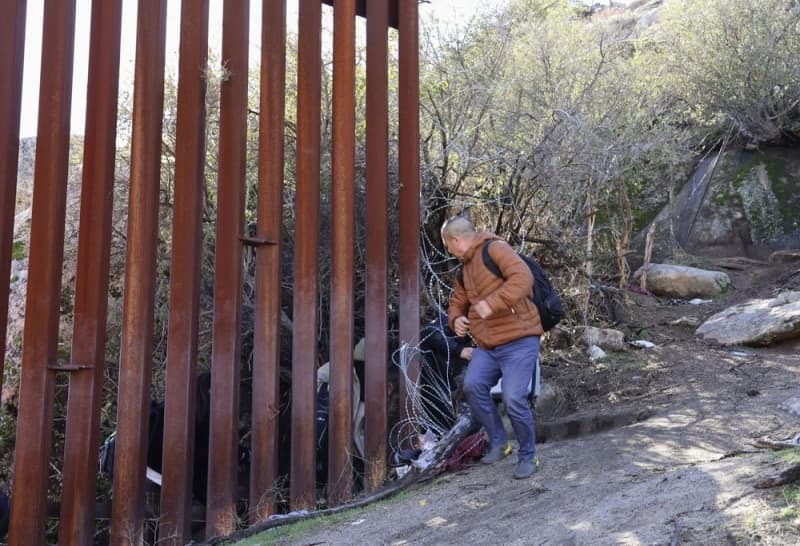 「国境の壁」の切れ目から米国に入る不法移民＝１月２３日、カリフォルニア州ハクンバホットスプリングス（共同）