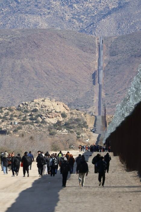 「国境の壁」に沿って歩く不法移民＝１月２３日、米カリフォルニア州ハクンバホットスプリングス（共同）