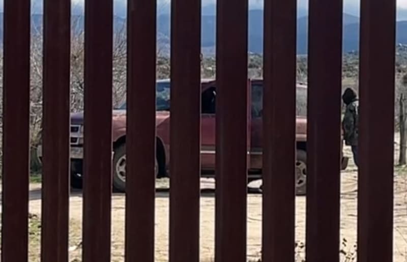 「国境の壁」のメキシコ側に到着した車。黒いフードを深くかぶる男は、闇業者「コヨーテ」だ＝１月、米ハクンバホットスプリングス（共同）