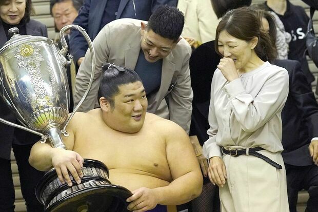 3月24日、優勝を決めて賜杯を手にする尊富士と、チケットが取れずに終了後の支度部屋で対面した母親の石岡桃子さん（右）
