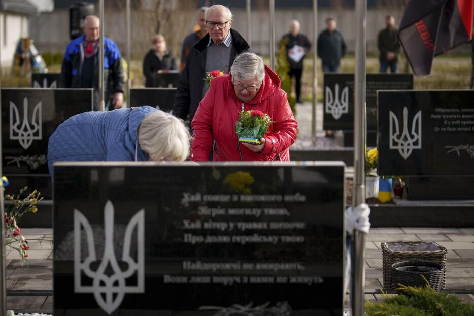 3月31日、ウクライナ・ブチャでロシア占領下に犠牲となった人々を追悼する式典が開かれ、戦死したウクライナ兵の墓に花を供える親族（AP＝共同）