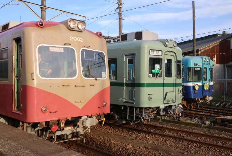 銚電の現役車両そろい踏み。手前から仲ノ町駅に到着した２０００形２００２編成、車庫の敷地に停車中の２２０００形と３０００形。２０００形と３０００形は京王電鉄から伊予鉄道を経て銚電入りした車両のため、今回の２２０００形デビューでは「中古の中古でない車両の導入は約３０年ぶり」と〝新しさ〟をアピールしている