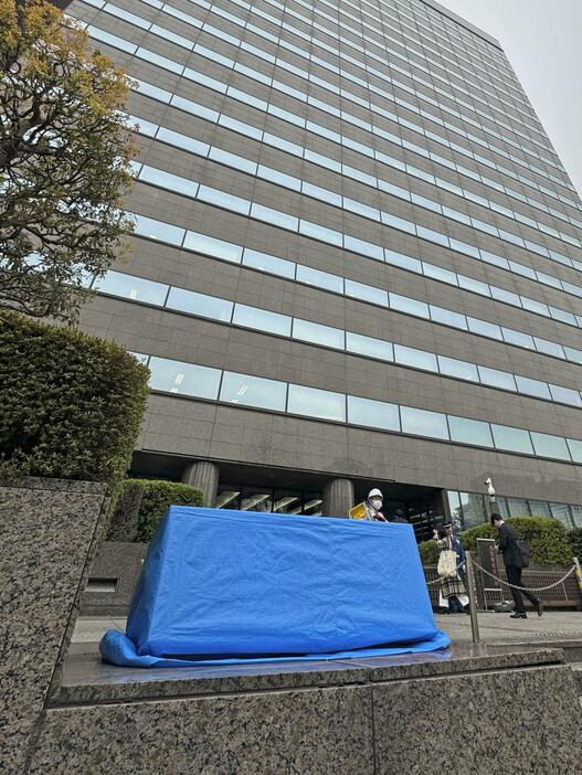 スプレーで汚損され、ブルーシートで覆われた「法務省」の石看板＝3日午前、東京・霞が関