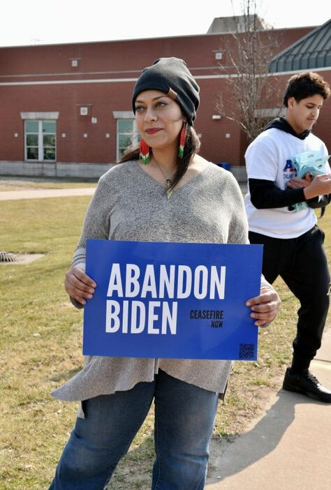 米ミシガン州ディアボーンの予備選投票所前で「バイデンを見捨てよう」と書かれたプラカードを持つサムラ・ルクマンさん＝２月、（共同）