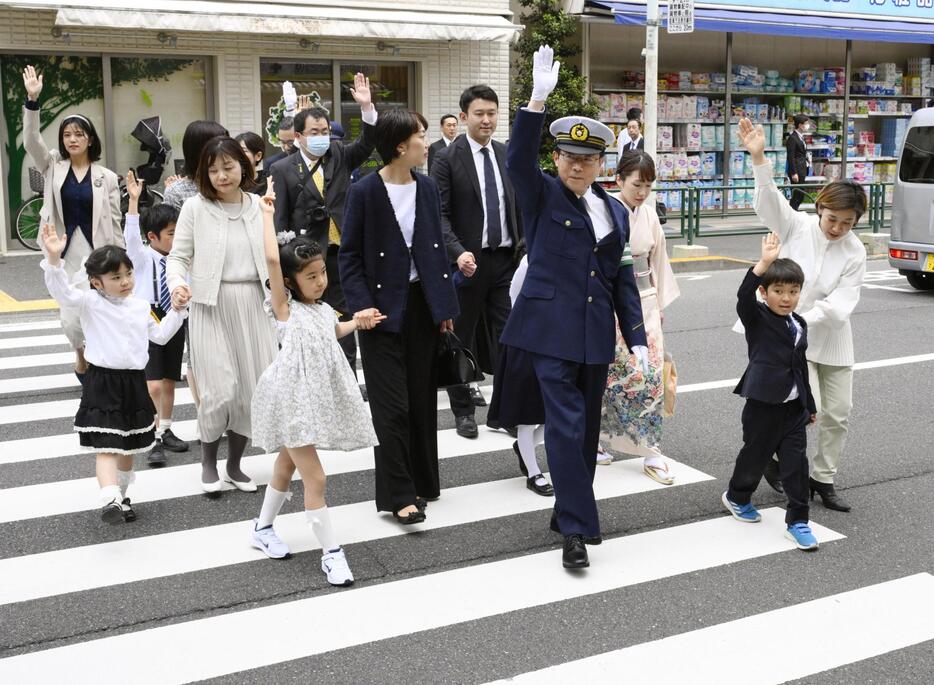 根津小学校の新1年生らと手を上げて横断歩道を渡る警視庁の緒方禎己警視総監（右から4人目）＝8日午後、東京都文京区