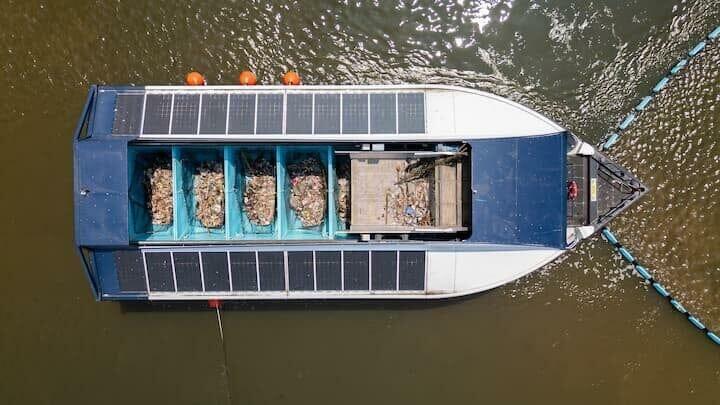 チャオプラヤー川で稼働する「インターセプター・オリジナル」　ボートに引き上げられたプラごみが、青いコンテナボックスへ自動投入される