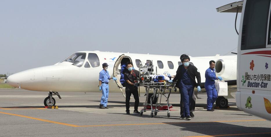 愛知県営名古屋空港で医療用ジェット機（奥）から降ろした男児をドクターカーに運ぶ医療スタッフ＝19日午後