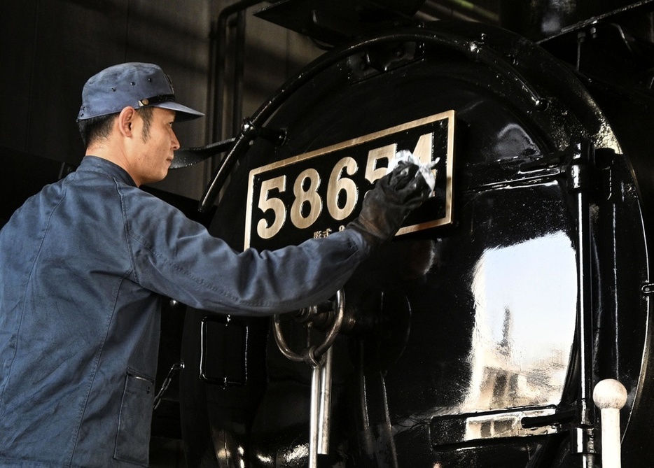 出発前に「ハチロク」の車体を拭き上げる機関助士＝2024年3月7日、熊本市のJR九州熊本車両センター