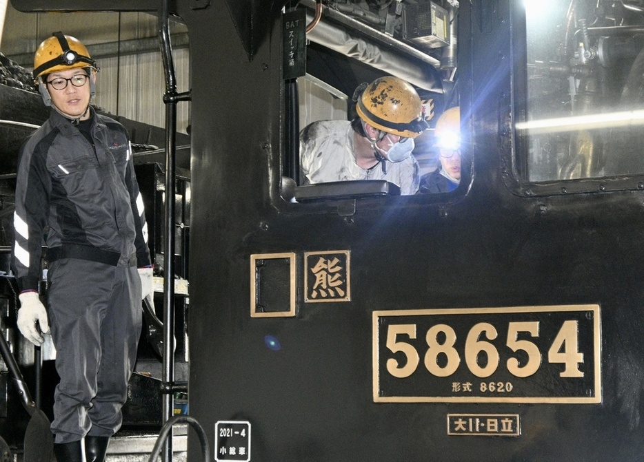 ハチロク」の車体を点検するJR九州エンジニアリングの山田恭輔さん（左）ら＝2024年2月、熊本市のJR九州熊本車両センター