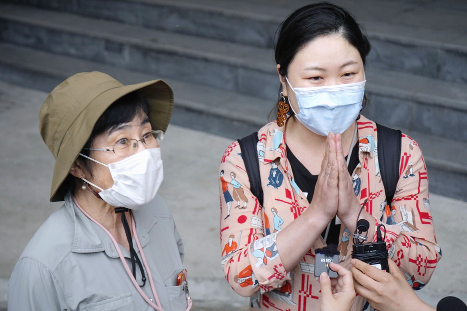 救助後、台湾の人々に感謝して手を合わせる娘（右）と母親の日本人親子＝5日、台湾東部・花蓮（共同）