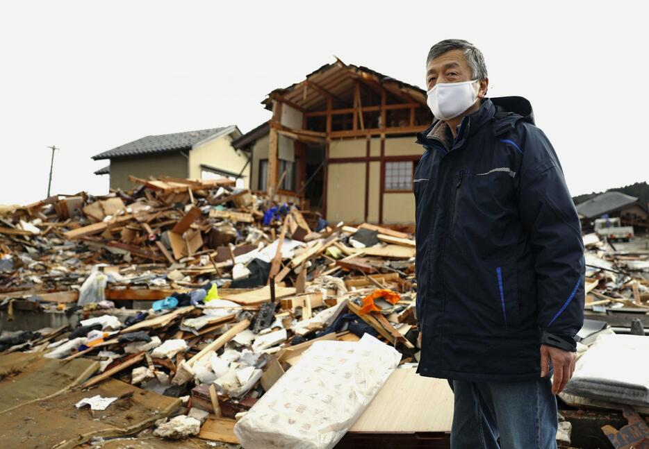 倒壊した自宅の前に立つ塩井一仁さん＝7日、石川県珠洲市