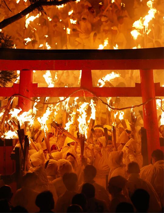 神倉神社の伝統の火祭り「お灯まつり」で、燃えさかるたいまつを手にする白装束の男衆＝6日夜、和歌山県新宮市