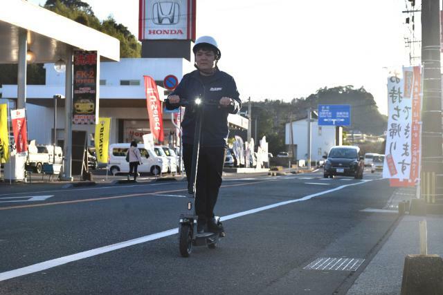 ヘルメットを着けて電動キックボードに乗る「オートパークＳＫＹ」の従業員＝宮崎市清武町加納