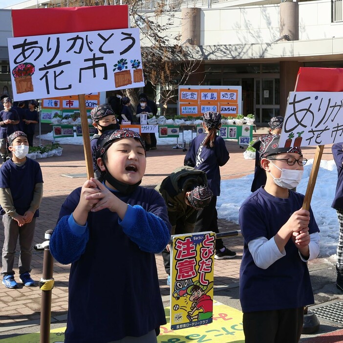 鉢植えの販売を知らせるプラカードを掲げ、支援を呼びかける児童たち＝8日午後1時16分、長野市通明小学校