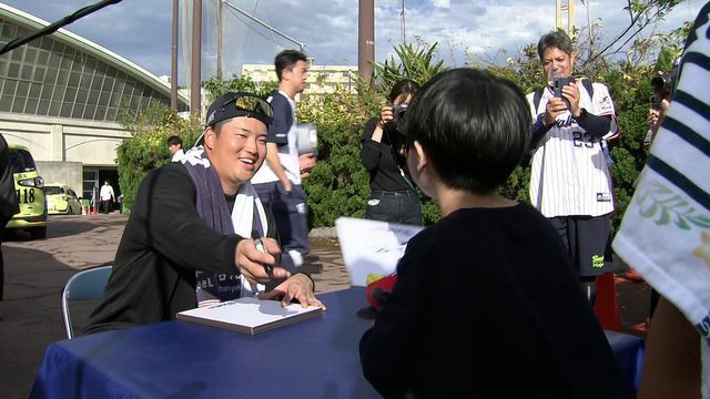 笑顔で子どもにサイン色紙を渡すヤクルト・村上宗隆選手