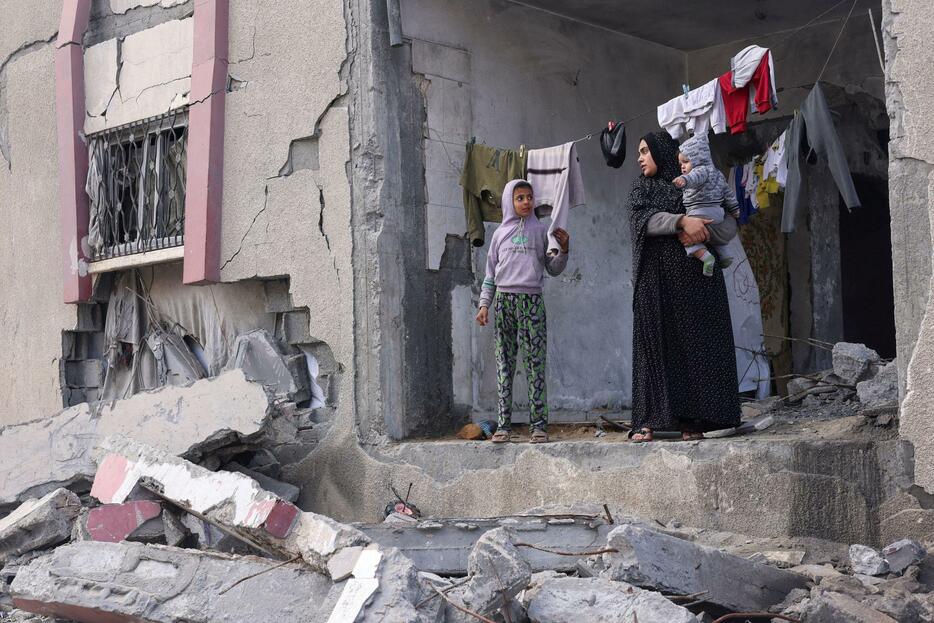 イスラエル軍の攻撃を受けて壊れた住宅に立つ女性ら＝27日、パレスチナ自治区ガザ南部ラファ（ロイター＝共同）