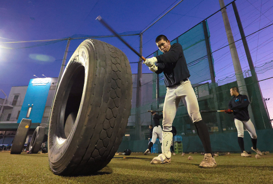 夕闇が迫るなか、タイヤをたたくトレーニングをする山梨学院の選手たち＝甲府市の同校砂田球場で２０２４年１月２７日、渡部直樹撮影