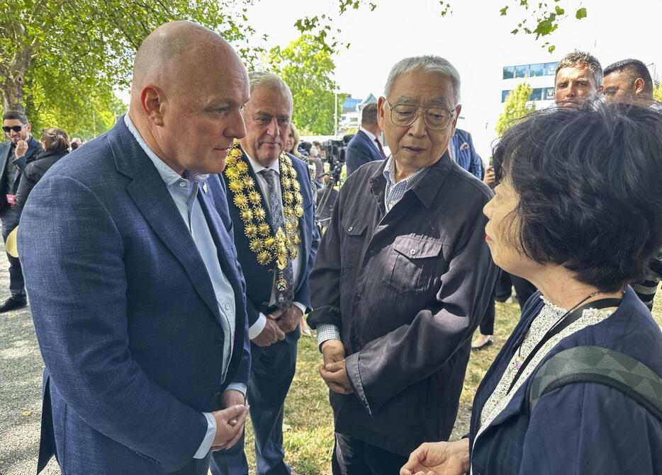 22日、ニュージーランド・クライストチャーチで開かれた追悼式で、ラクソン首相（左手前）と言葉を交わす故堀田めぐみさんの母聖子さん（右手前）と父和夫さん（共同）
