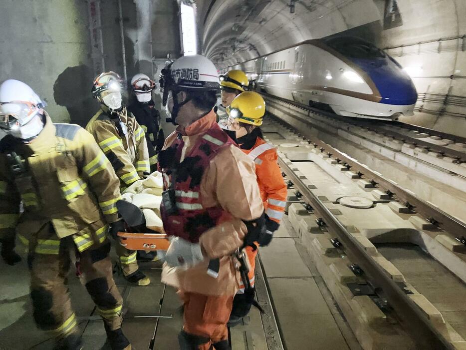 新北陸トンネルで実施された救護訓練で、乗客のけが人を担架に乗せて運び出す消防隊員＝22日午後、福井県南越前町