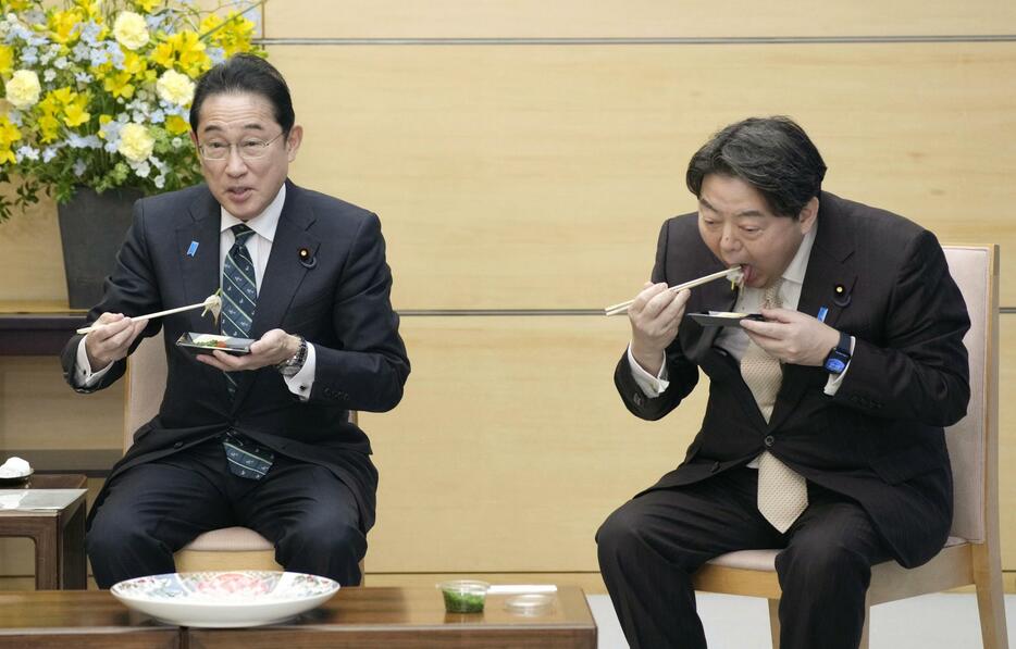 山口県下関市のフグ仲卸業者らと面会し、天然トラフグの刺し身を試食する岸田首相（左）と林官房長官＝21日午後、首相官邸