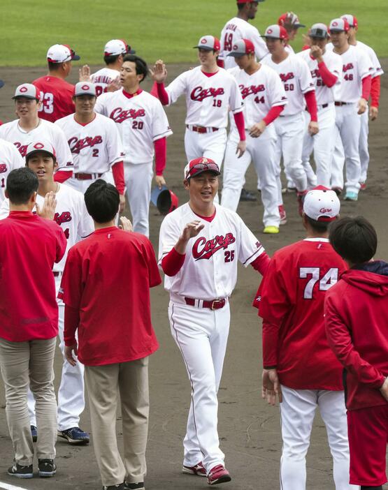 キャンプを打ち上げ、選手やスタッフらとタッチを交わす広島・新井監督（手前）＝沖縄