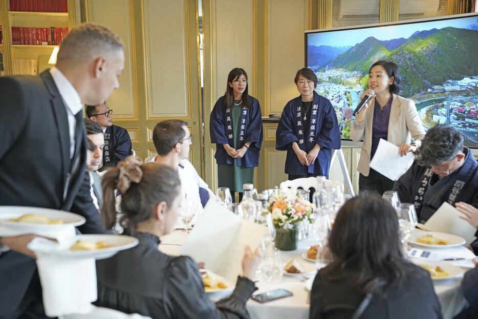 12日、パリで開かれた日本酒の試飲会で、日本酒をPRする奥飛騨酒造の営業担当の高木梨佐さん（奥左）と取締役の高木美賀子さん（同中央）（共同）